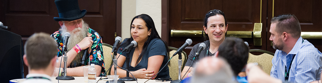 A four speaker panel sitting in front of microphones on a table